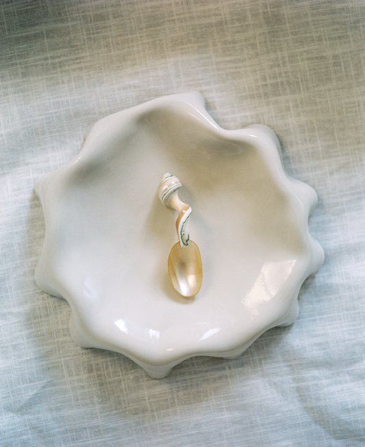 Assiette blanc cassé aux bords ondulés.