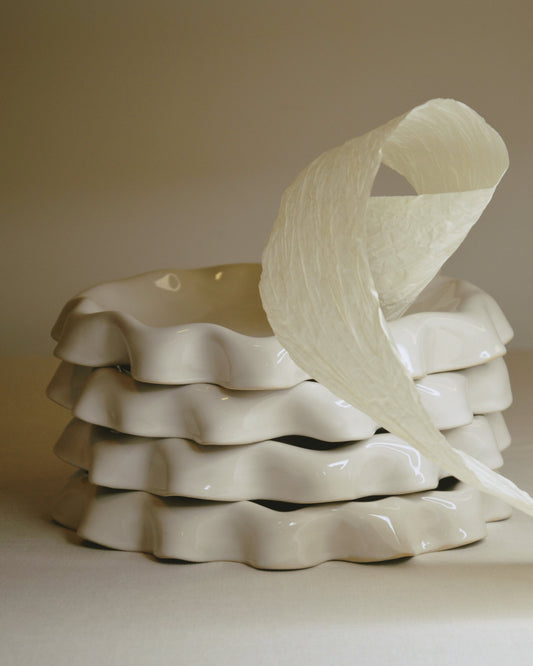 Assiette blanc cassé aux bords ondulés.