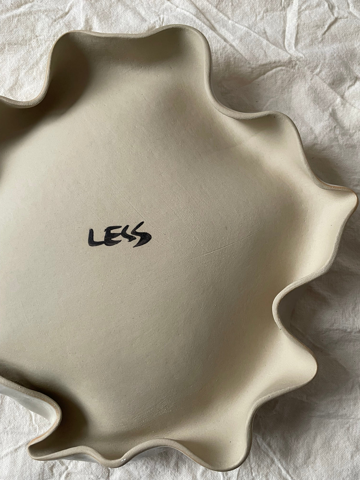 Assiette blanc cassé aux bords ondulés.