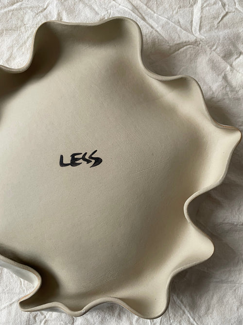 Assiette blanc cassé aux bords ondulés.