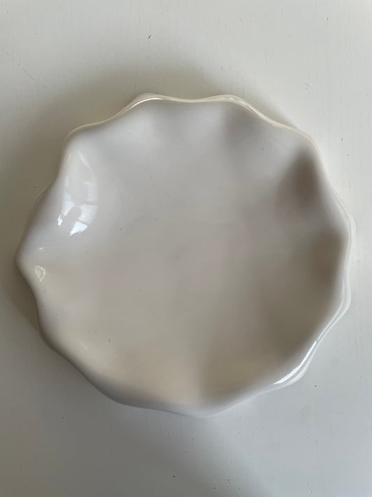 Assiette blanc cassé aux bords ondulés.