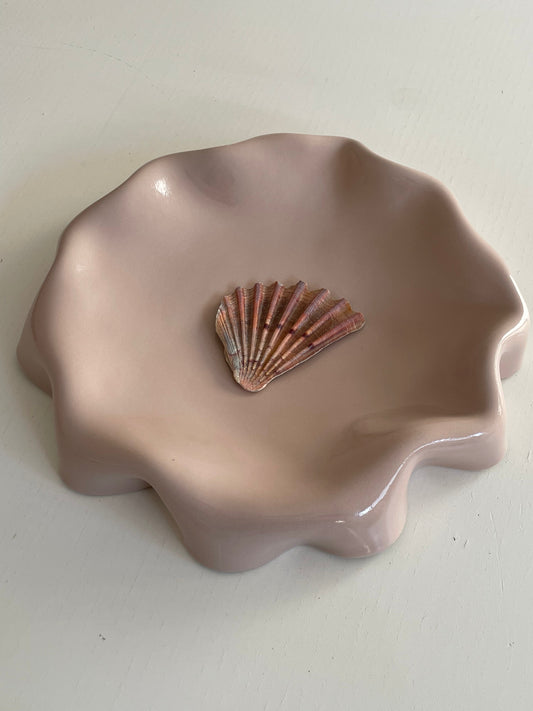 Assiette rose poudré aux bords ondulés.