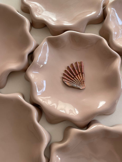 Assiette rose poudré aux bords ondulés.